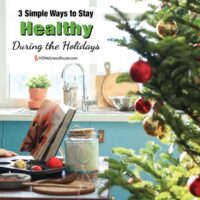 Opened cookbook on table with Christmas tree in kitchen with overlay: Ways to Stay Healthy During the Holidays