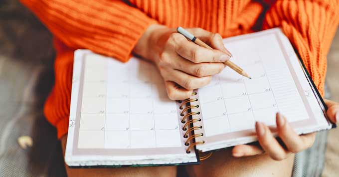 Woman in orange sweater checking a calendar.