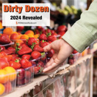 Close up of woman's hand grabbing strawberries in a grocery store.