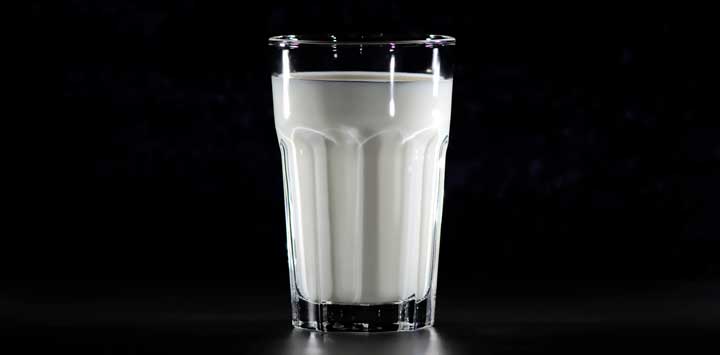 Glass of milk with a black background.