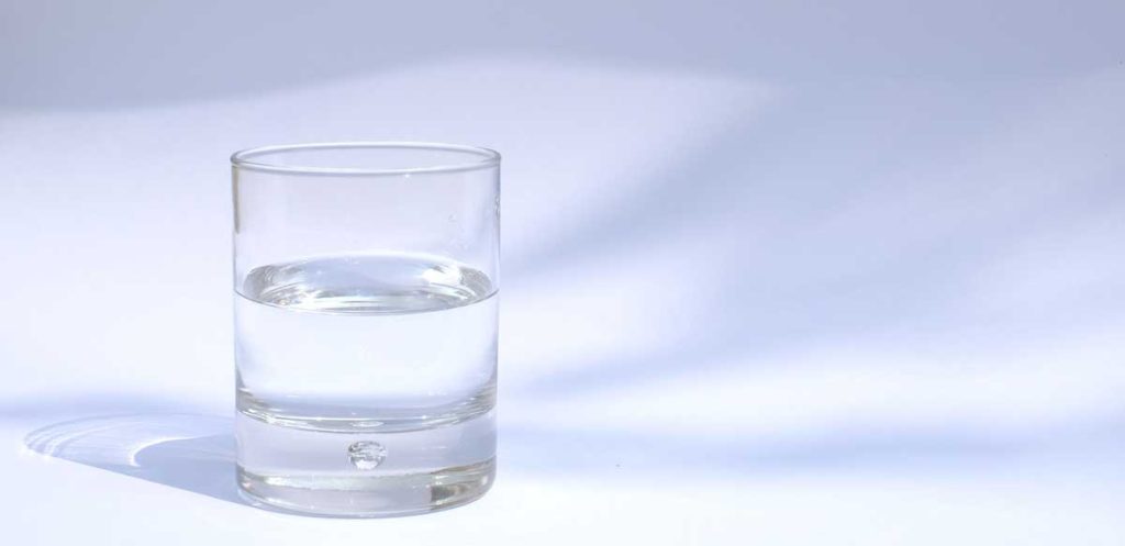 Half glass of water with bluebackground.