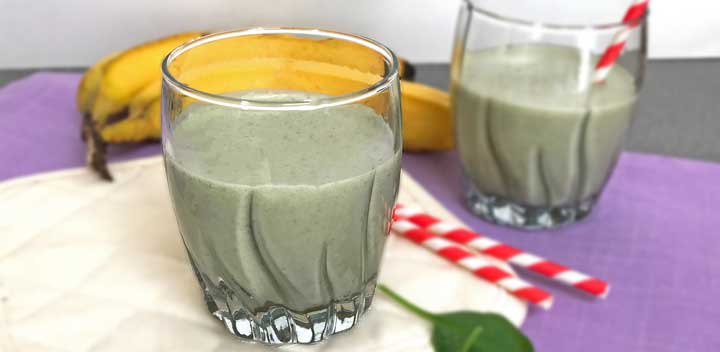 Green smoothie with a banana in the background.