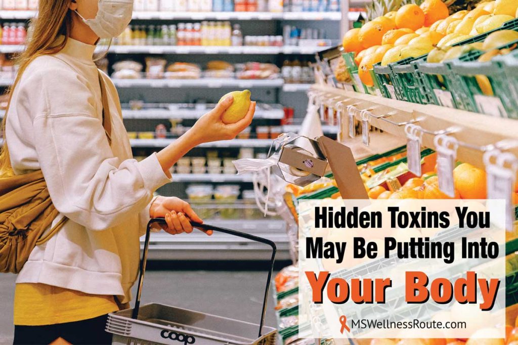 Woman wearing mask buying holding fruit in grocery store with overlay: Hidden Toxins You May Be Putting Into Your Body