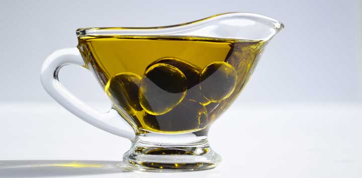 Olives in a glass cup of olive oil.