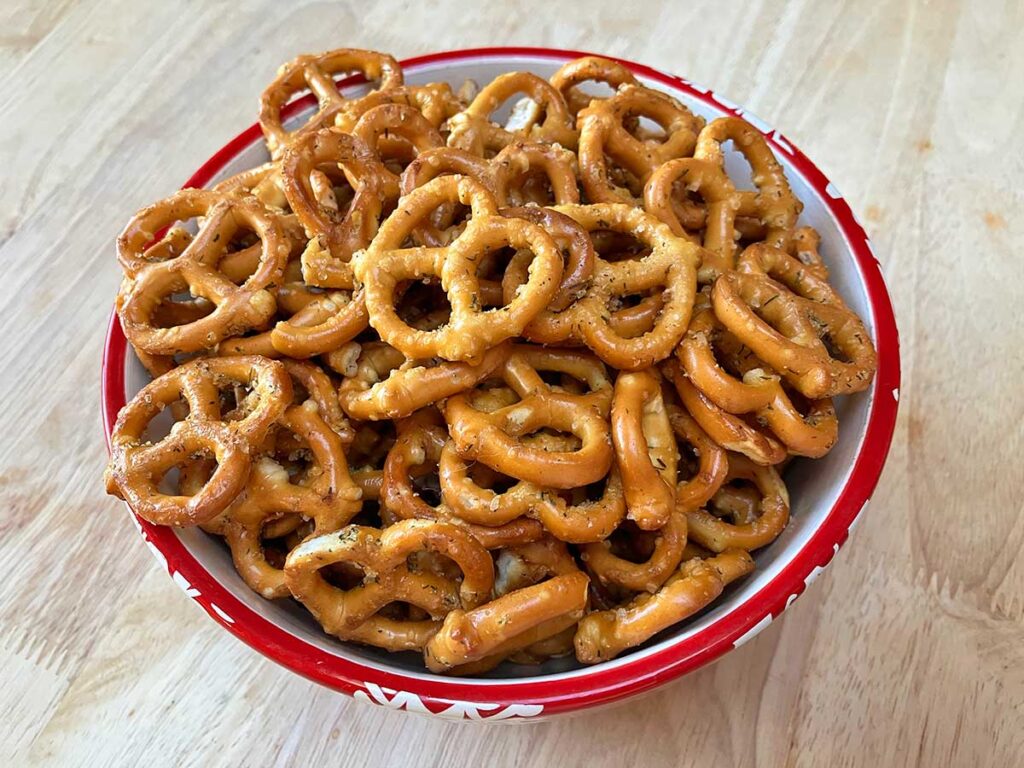 Red and white bowl full of seasoned pretzels.