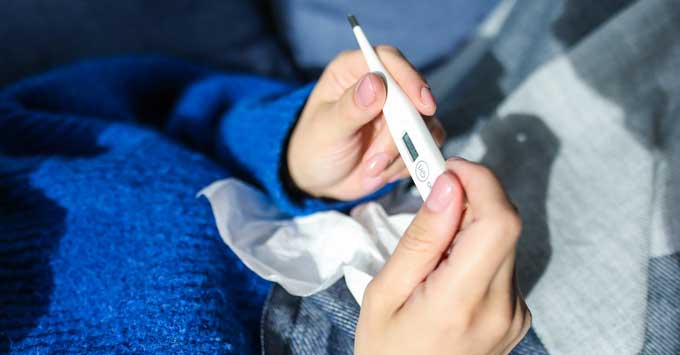 Sick person holding thermometer.