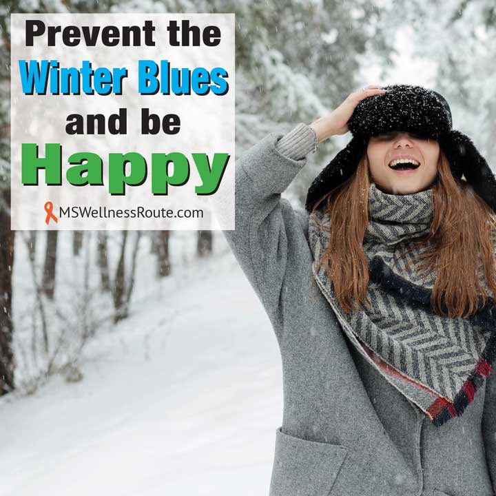 Young woman smiling holding her hat in the snow.