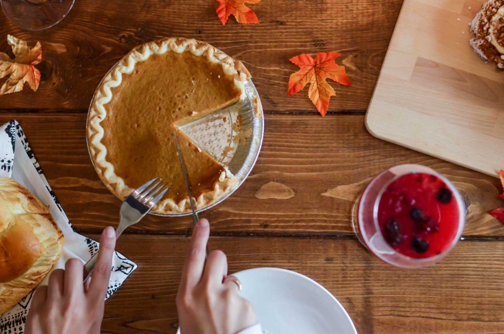 Woman slicing a piece of pumpkin pie.