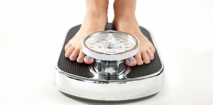 Woman with blue toenails stepping on a scale.