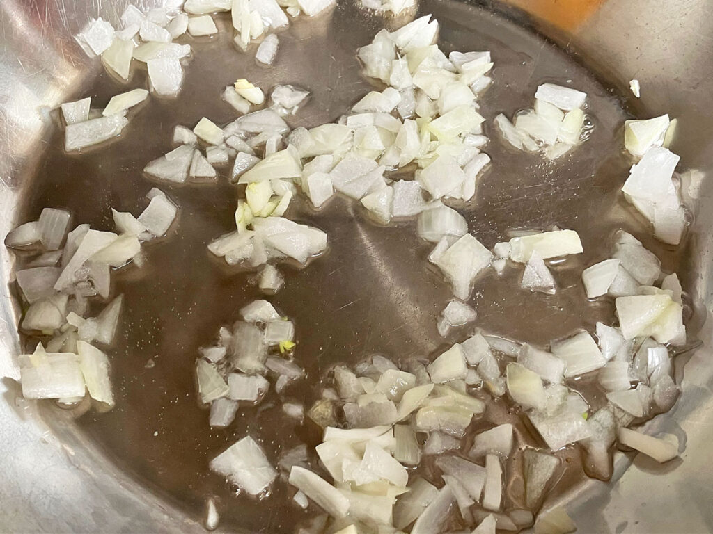 Onions sautéing in water in a pan.