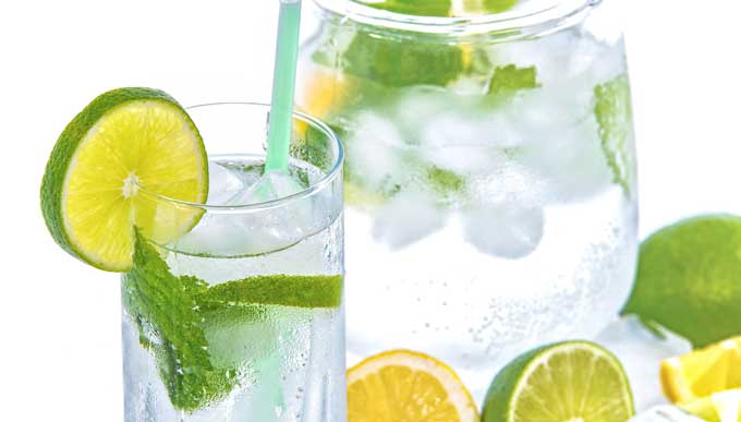 Pitcher and glass of water with slice of lime and mint leaves.