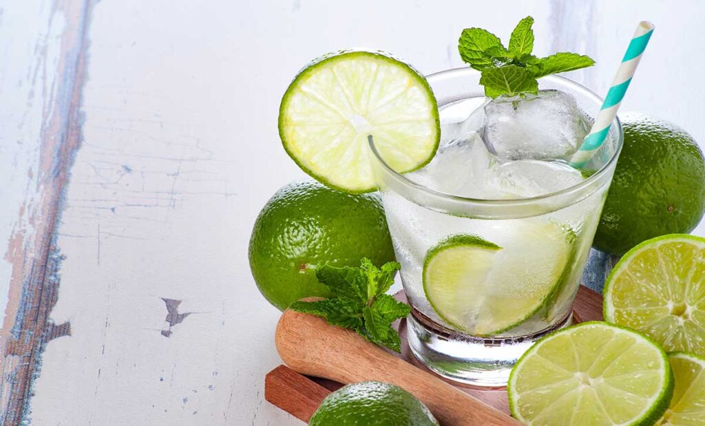 Glass of water with lime, ice, mint, and a straw.