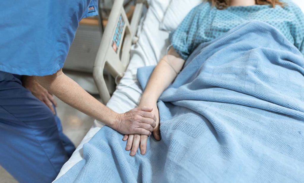 Woman in hospital being comforted by a nurse.