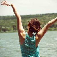 Happy woman with arms in the air overlooking a river.