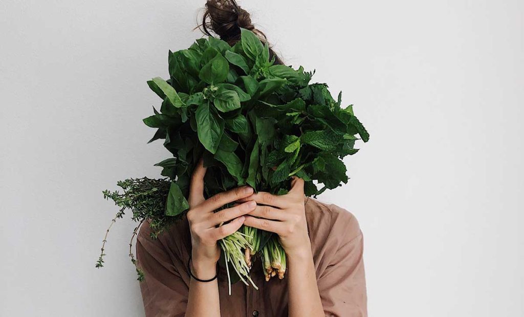 Woman hiding her face behind leaves.