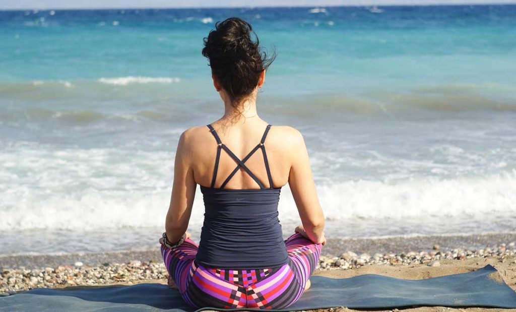 Woman meditating on beach.