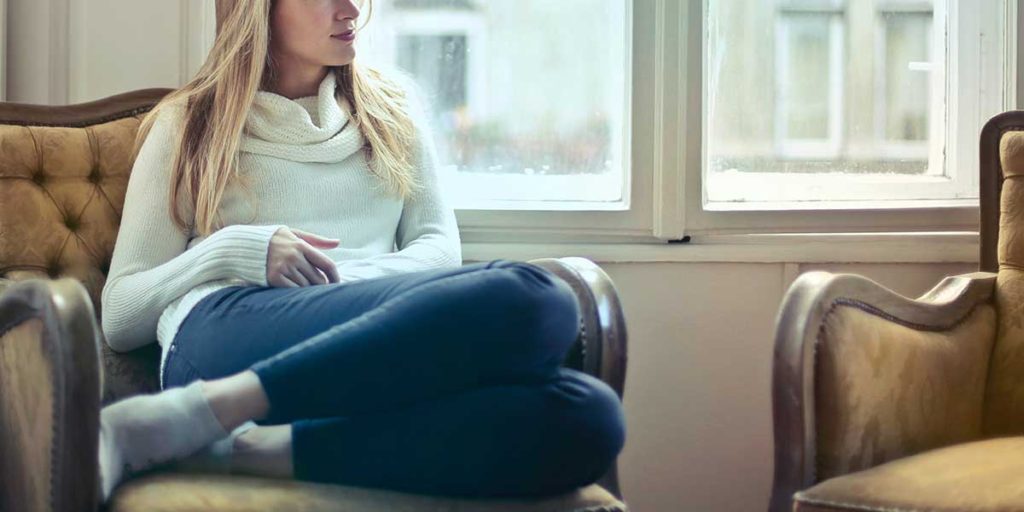 Young blond woman sitting in vintage gold chair.