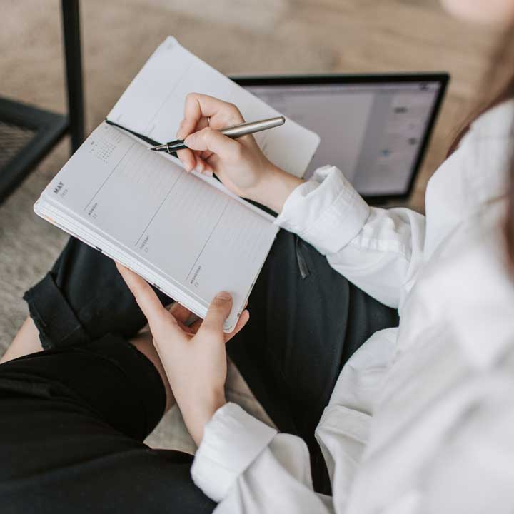 Woman taking notes in notebook.