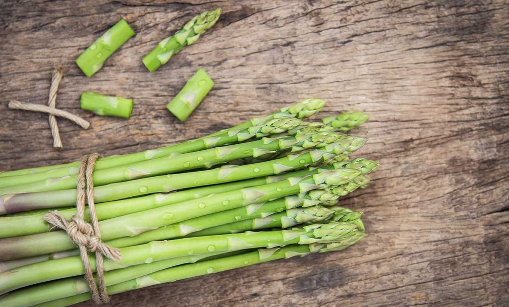 Asparagus tied with string on wooden table.