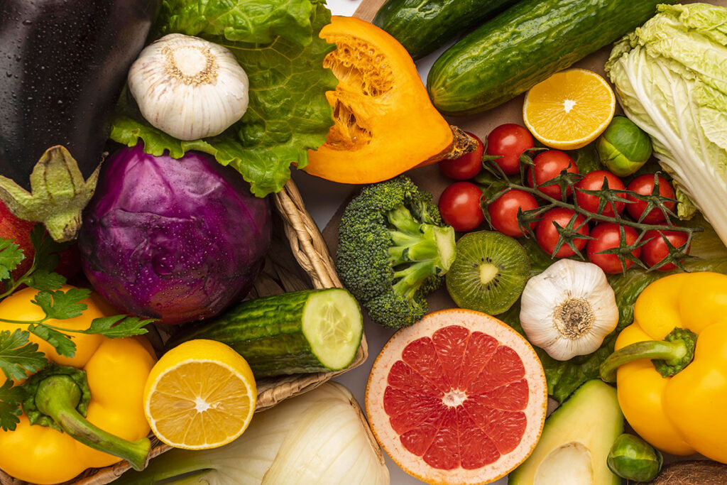 Looking down at an assortment of fruits and vegetables such as lemons, grapefruit, cabbage, and garlic.