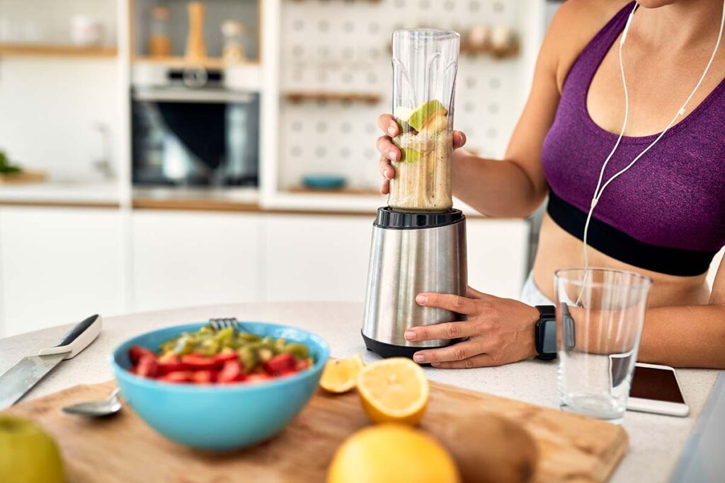 Woman in sports top making a smoothie.