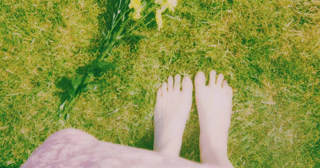 Woman in dress barefoot in grass.