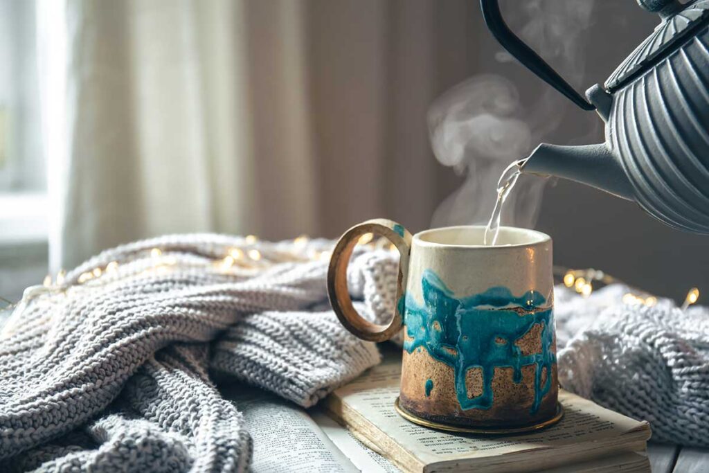 Beautiful handmade ceramic cup on a blurred background with a knitted element.