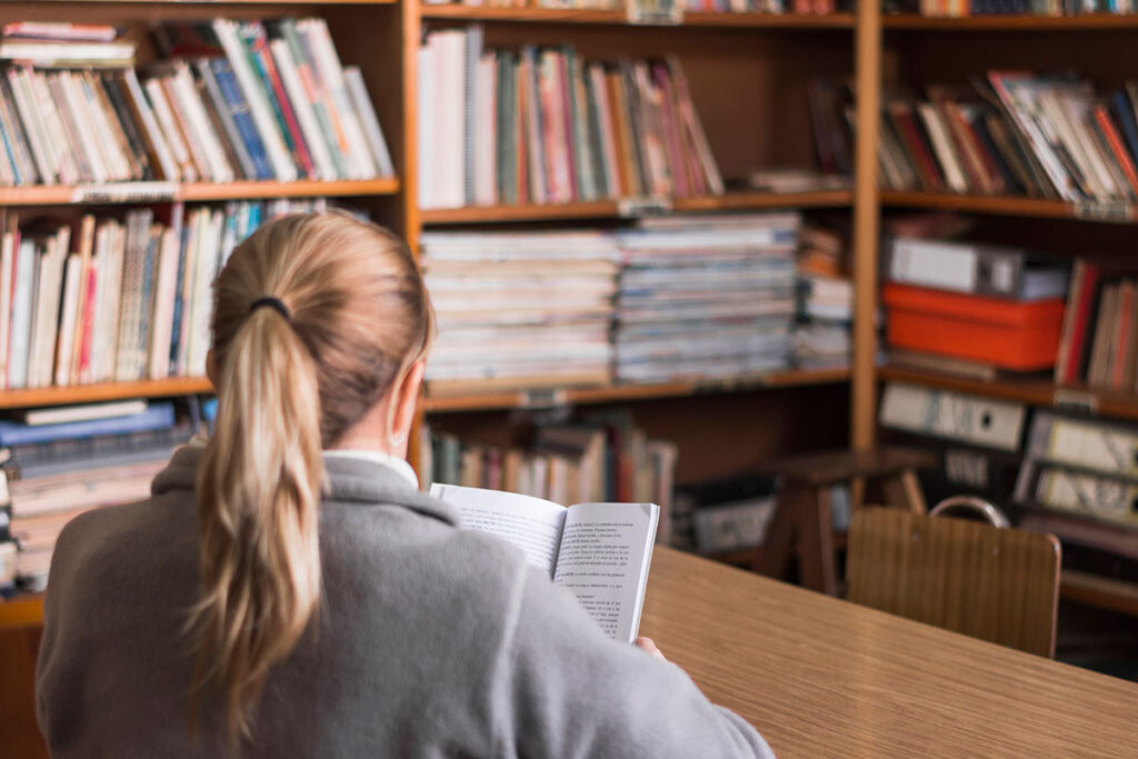 Back of woman reading a book at the library.