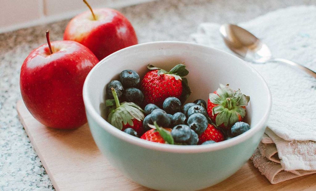 Bowl of berries and two apples.