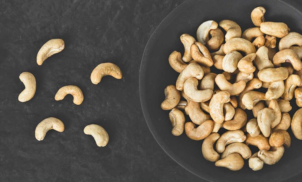 A bowl of cashews with six on the table.