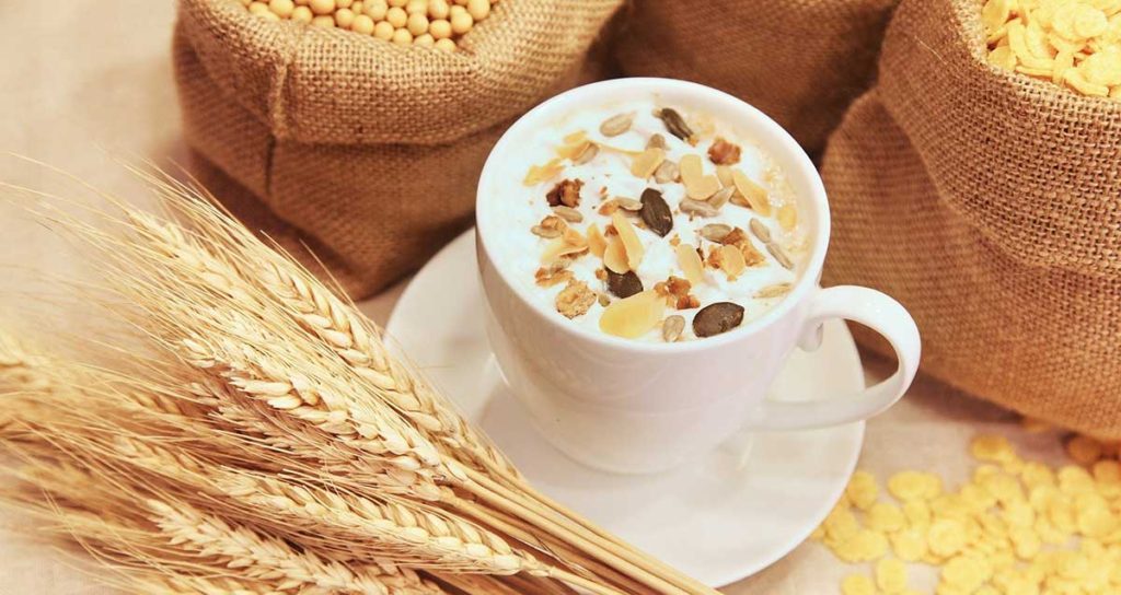 A cup of muesli surrounded by grains.