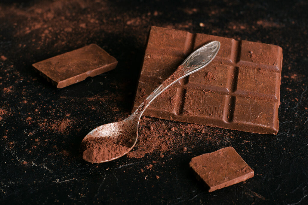 Chocolate bar with spoon full of cocoa powder.