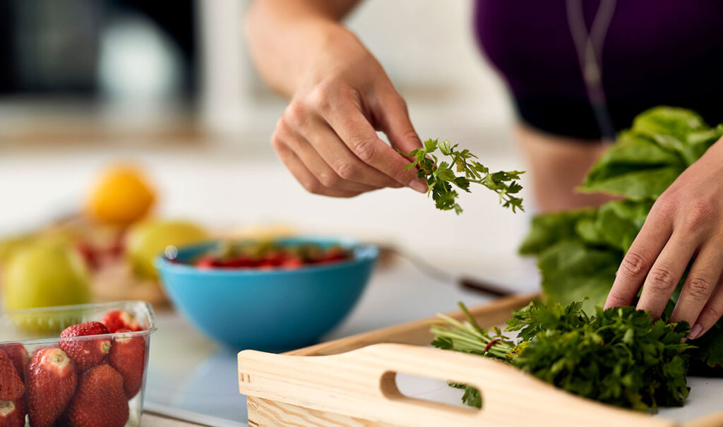 Closeup of woman using parsley while making healthy food.