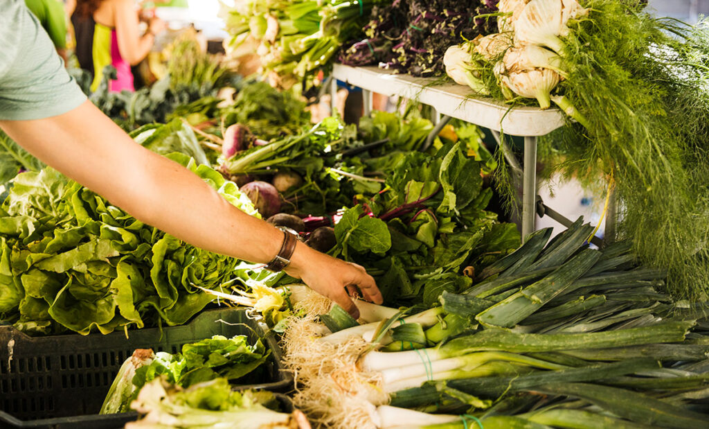 Hand choosing a leek at the market.