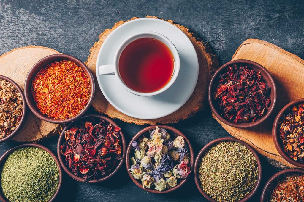 Cup of tea with herbs in bowls next to it.