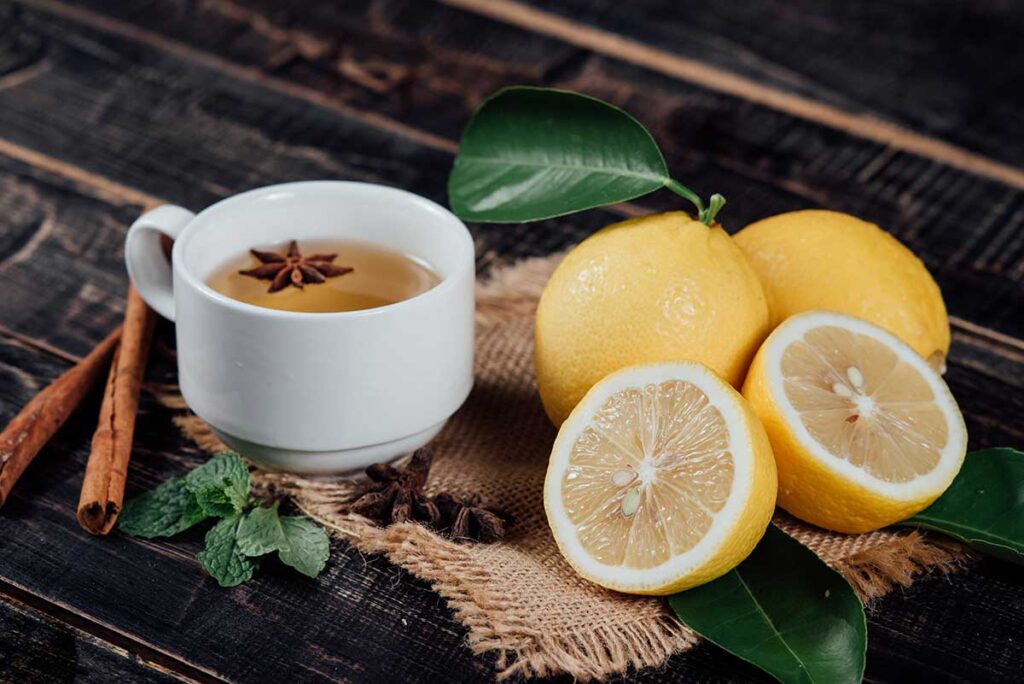 Cup of tea with lemons and cinnamon sticks.