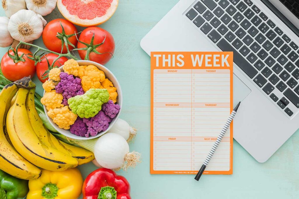 Laptop with veggies and mean planning paper.