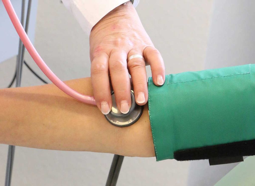 Doctor checking woman's blood pressure.