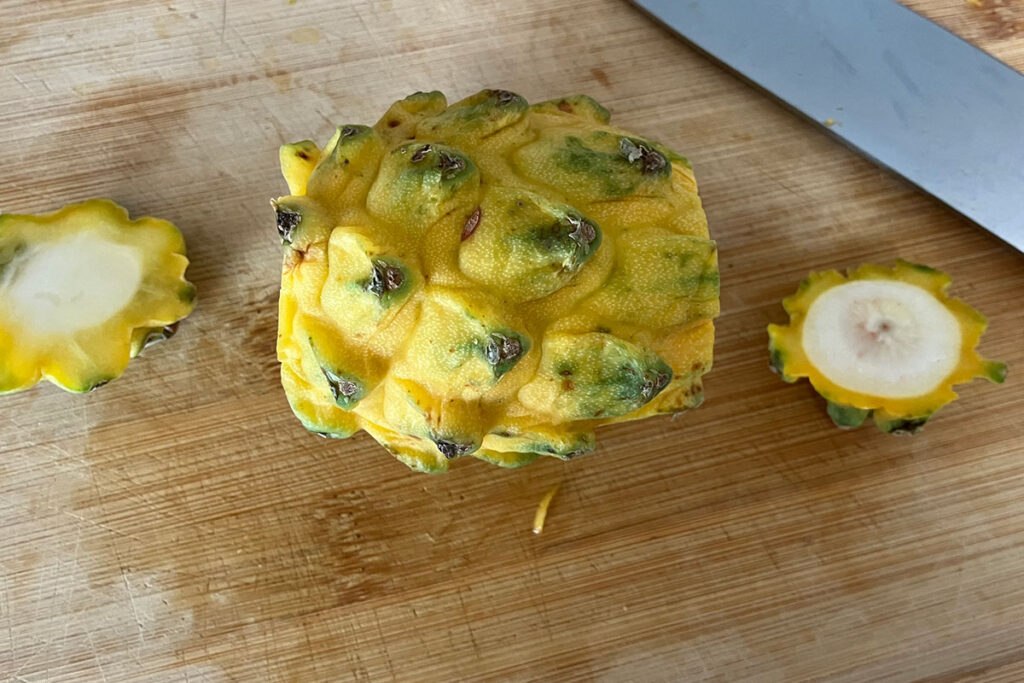 Dragon fruit with ends cut off on a cutting board.