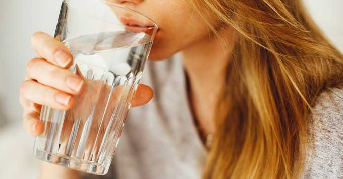 A woman drinking a glass of water.