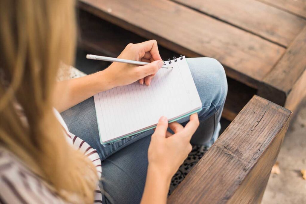 Elevated view of woman writing in a notebook.