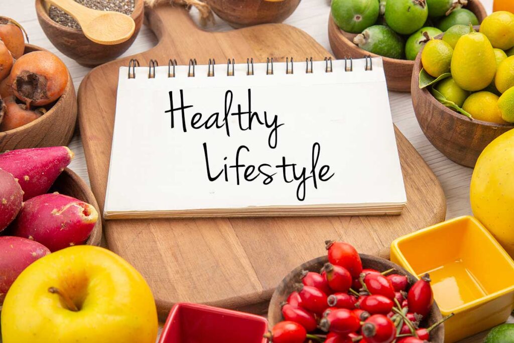 Fresh fruits surrounding a notebook that says "Healthy Lifestyle."