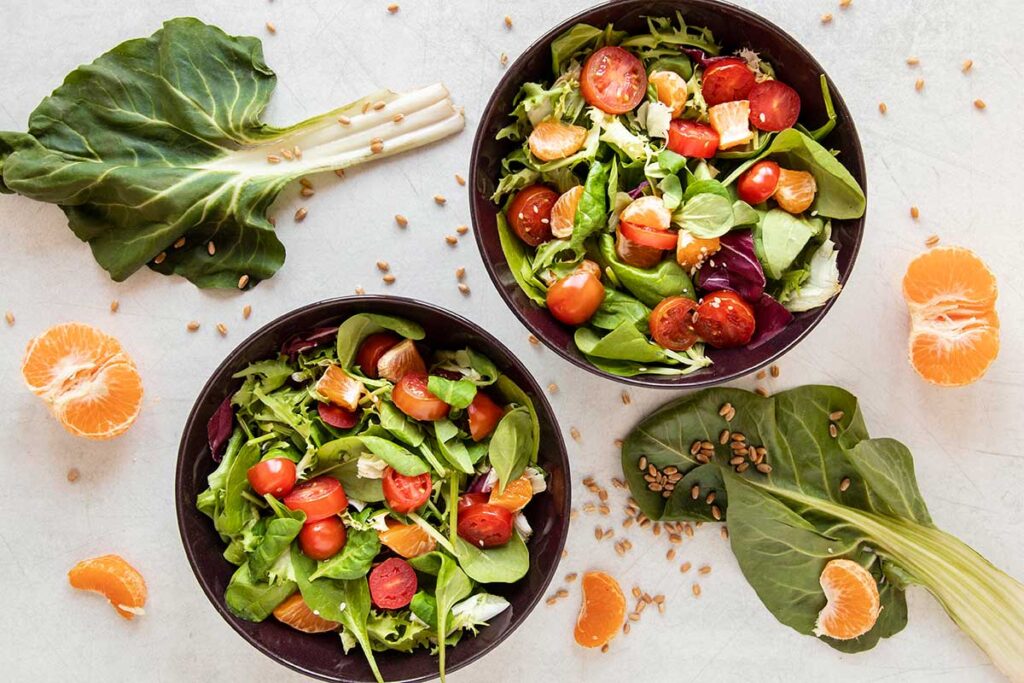 Fresh salad with tomatoes, orange slices, and seeds.