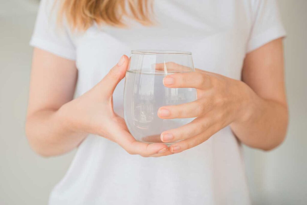 Young woman holding glass of water.