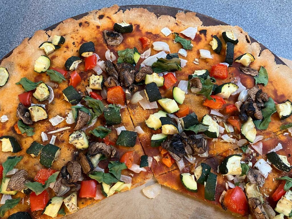 Homemade veggie pizza on a pizza stone.