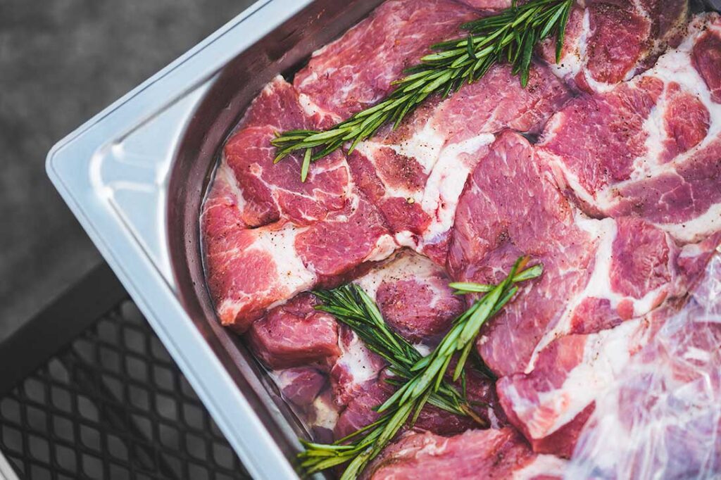 Marinated beef in a pan with herbs.