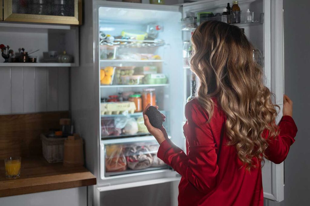 Woman checking fridge to organize.