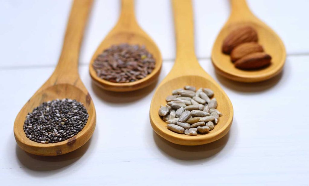 Nuts and seeds on wooden spoons.