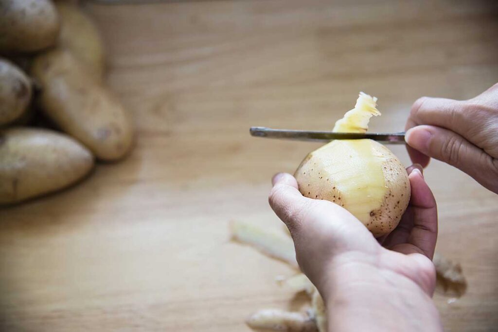 Close up of woman peeling a potato.