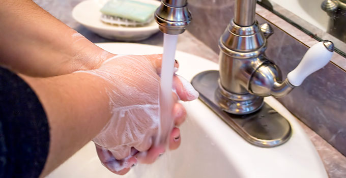 Woman washing her hands in the bathroom sink.